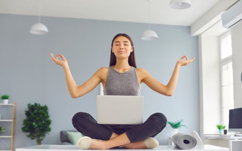 girl with laptop on lap and in meditating pose