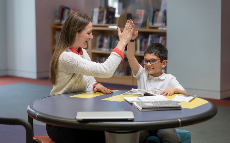 woman tutor high fiving young student